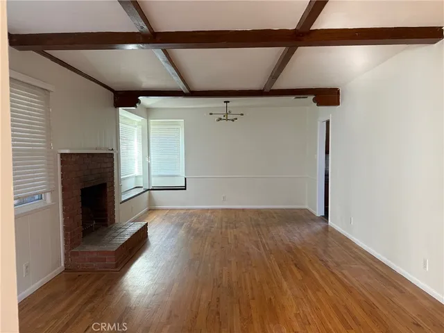 a view of empty room with wooden floor and fireplace
