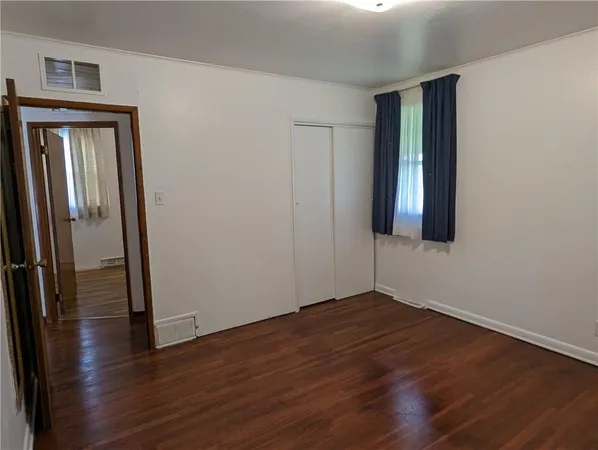 an empty room with wooden floor and closet