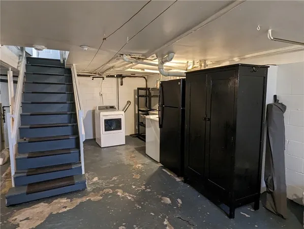a view of a refrigerator in kitchen and an empty room with wooden floor