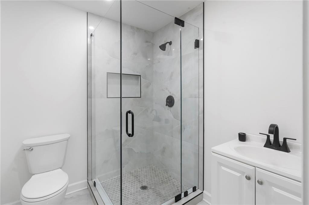 403 Rockbridge Road Southwest Lilburn, GA 30047 - Photo 72 of 77 a bathroom with a toilet sink vanity and shower