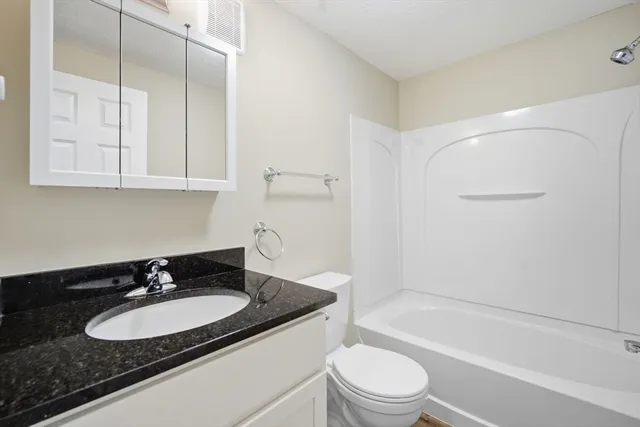 a bathroom with a granite countertop sink toilet and shower