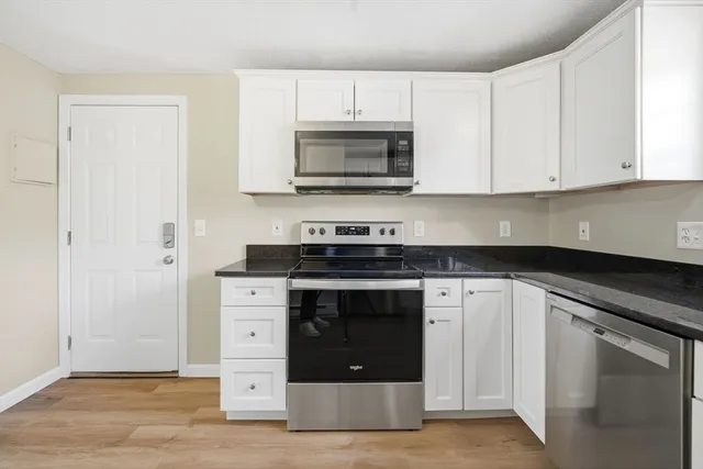 a kitchen with granite countertop white cabinets and stainless steel appliances