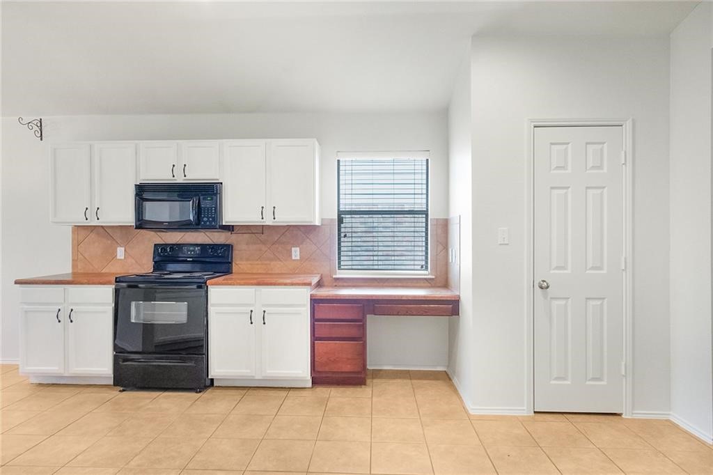 913 Cindy Lane Leander, TX 78641 - Photo 6 of 28 a kitchen with granite countertop white cabinets and stainless steel appliances