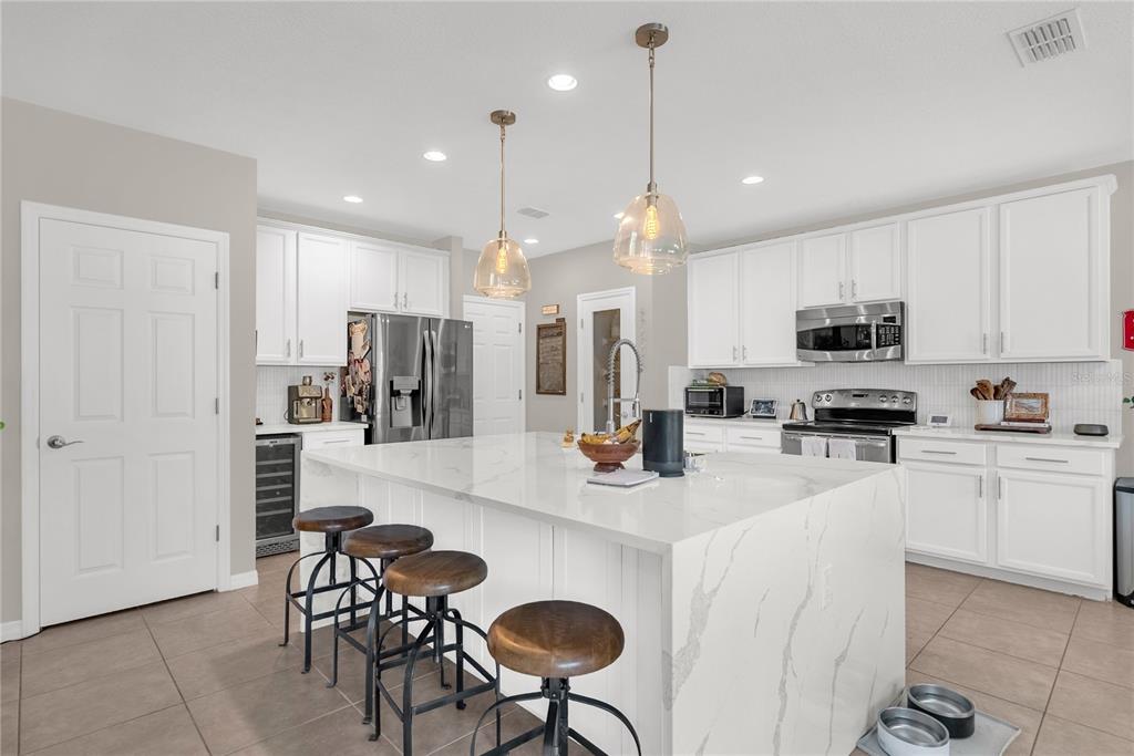 2096 Water Tupelo Way Ocoee, FL 34761 - Photo 6 of 32 a kitchen with stainless steel appliances granite countertop a refrigerator a stove a sink a island a dining table and chairs