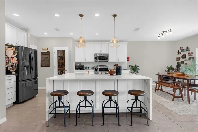 a kitchen with stainless steel appliances kitchen island granite countertop a table chairs microwave and cabinets