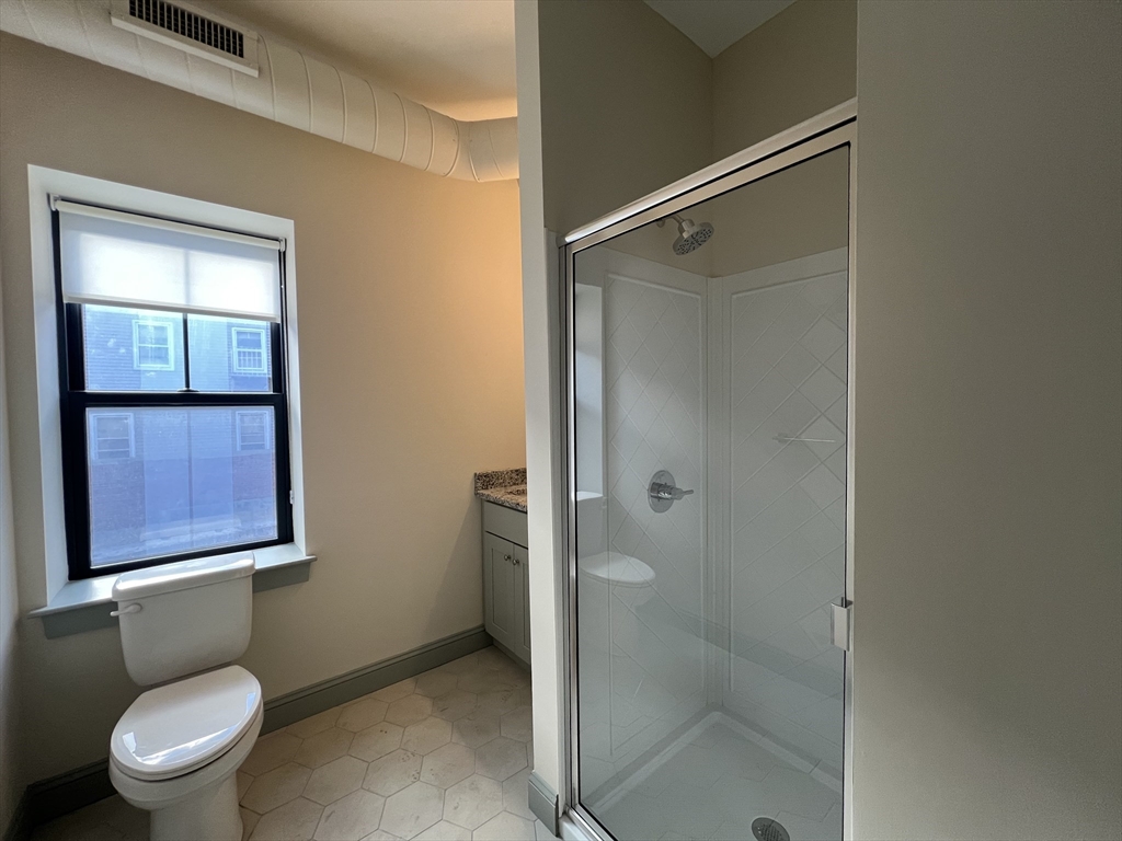160 Seabury Street, Unit 5 Fall River, MA 02720 - Photo 8 of 10 a bathroom with a granite countertop toilet and a shower
