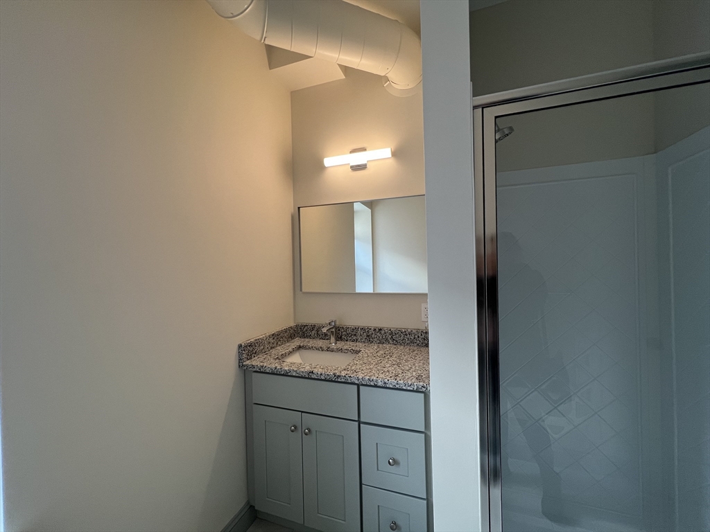 160 Seabury Street, Unit 5 Fall River, MA 02720 - Photo 9 of 10 a bathroom with a granite countertop sink and a mirror