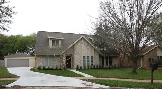 a front view of a house with a garden and trees