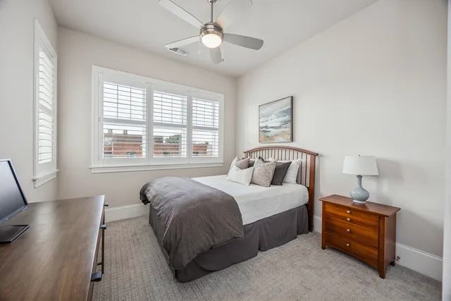 a spacious bedroom with a bed and a table in it with window