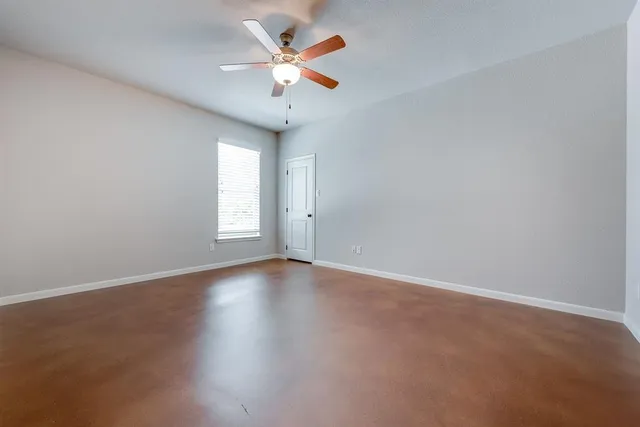 an empty room with a window and a fan