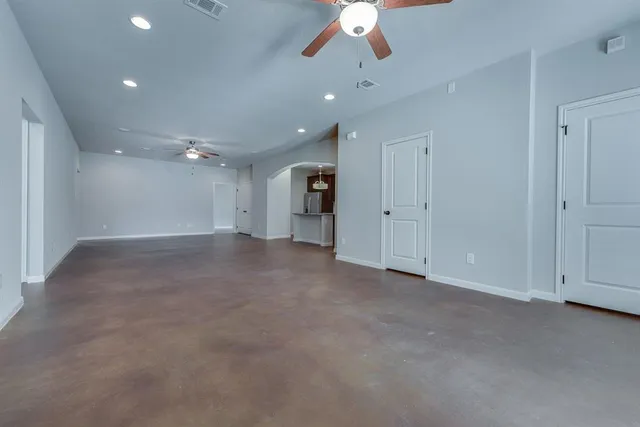 an empty room with an entryway and chandelier fan