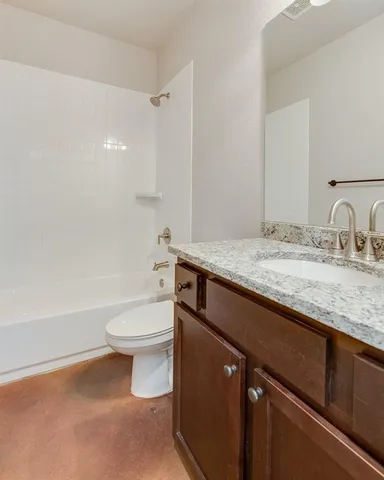 a bathroom with a granite countertop toilet sink and mirror