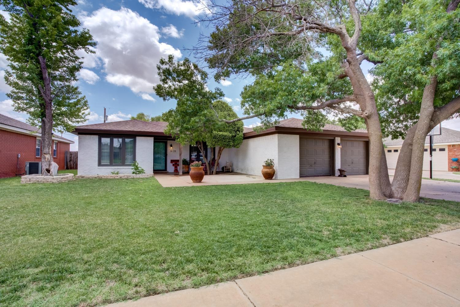 a front view of a house with a garden and trees