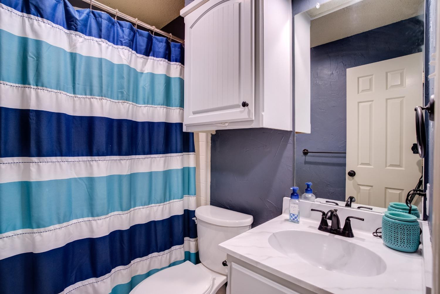 1428 5th Street Shallowater, TX 79363 - Photo 19 of 30 a bathroom with a sink a toilet and shower curtain