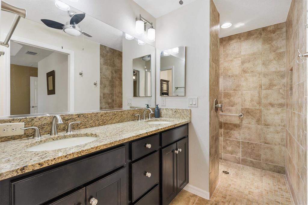 7351 Southeast 169th Cote Loop The Villages, FL 32162 - Photo 16 of 32 a bathroom with a granite countertop sink a mirror and a shower