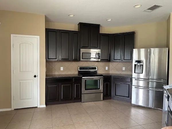 a kitchen with stainless steel appliances granite countertop a refrigerator and a stove top oven