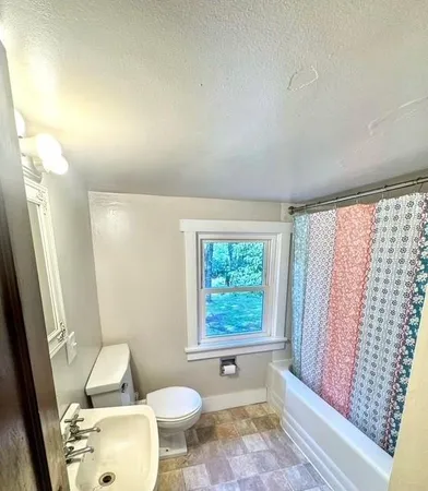 a bathroom with a granite countertop sink toilet a mirror and a tub