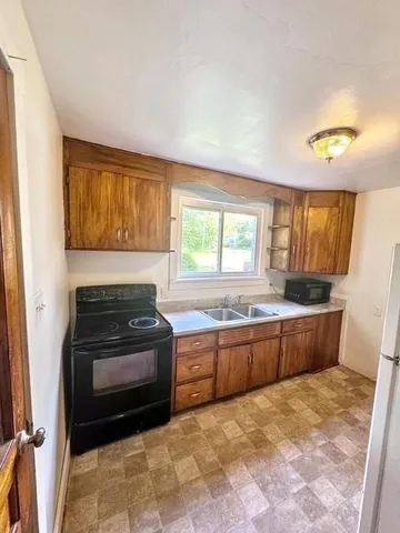 a kitchen with granite countertop a stove top oven sink and cabinets