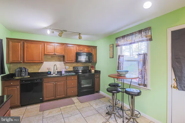 a kitchen with stainless steel appliances granite countertop a stove a refrigerator a sink a dining table and chairs with wooden floor