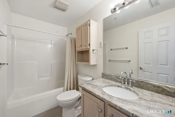 a bathroom with a granite countertop sink toilet and shower