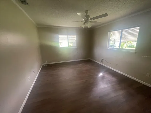 an empty room with wooden floor fan and windows