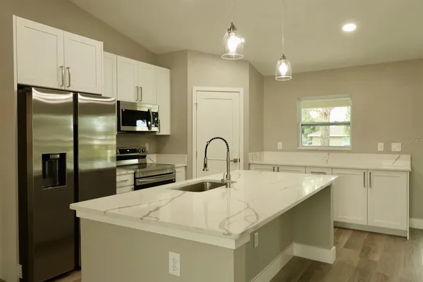 a large kitchen with stainless steel appliances a refrigerator a stove and a sink