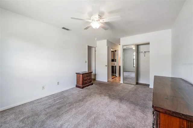 an empty room with closet and a ceiling fan
