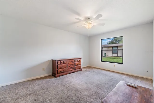 a view of an empty room with chandelier fan and window