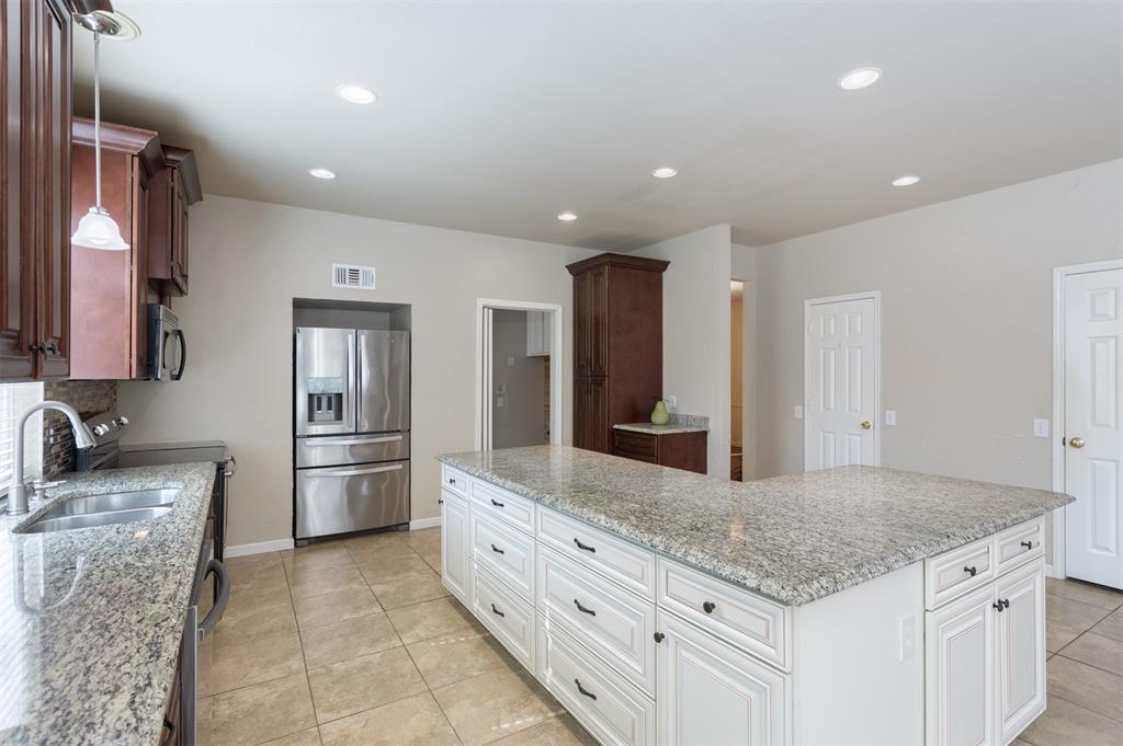 3306 Harbor Pointe Drive Rowlett, TX 75088 - Photo 15 of 40 Oversized granite island and cabinetry, doors to pantry and storage closet
