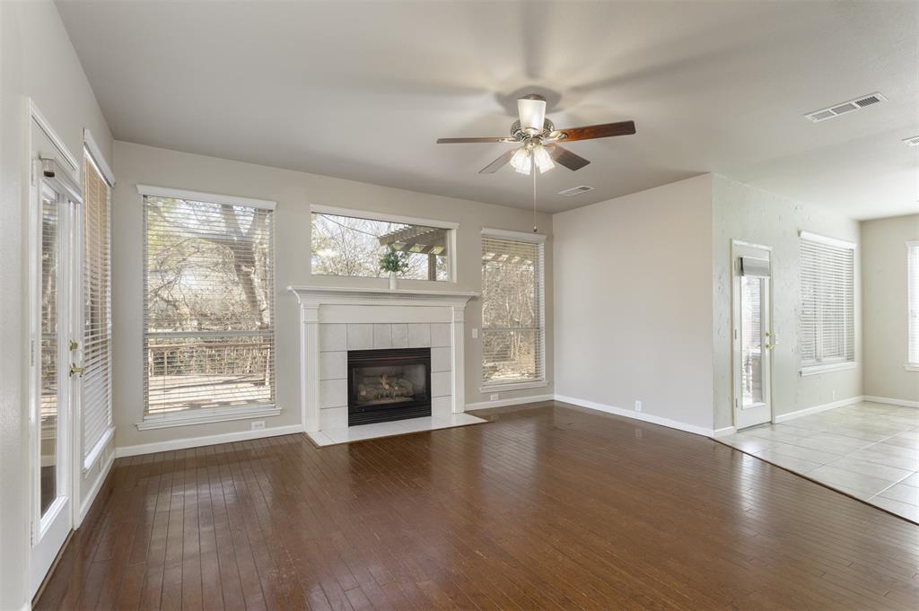 3306 Harbor Pointe Drive Rowlett, TX 75088 - Photo 8 of 40 Walls of large windows overlook the backyard, ceiling fan, gas log fireplace and open view to kitchen