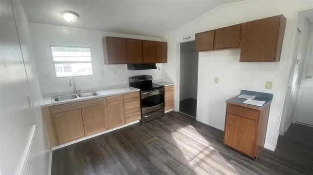 a kitchen with a sink cabinets stainless steel appliances and wooden floor