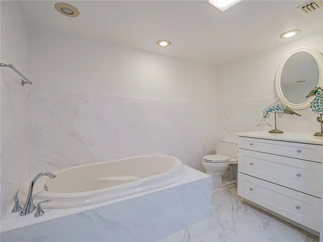 a bathroom with a bathtub sink vanity mirror and toilet
