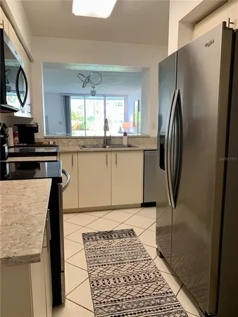 a kitchen with stainless steel appliances granite countertop a refrigerator a stove and a sink with granite countertops