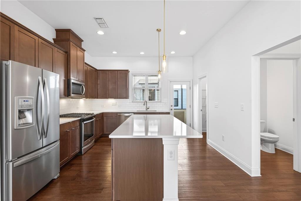 1752 Morningtide Lane Northeast Atlanta, GA 30324 - Photo 22 of 57 a large kitchen with stainless steel appliances kitchen island granite countertop a refrigerator a sink a stove and oven with wooden floors