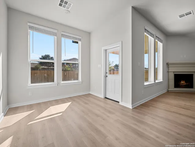 a view of an empty room with window and wooden floor