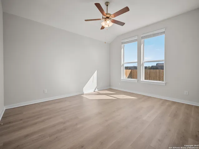 a view of an empty room with a window and wooden floor