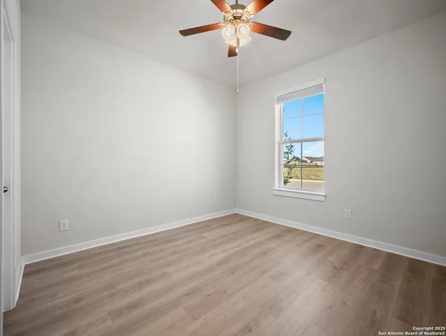 an empty room with wooden floor fan and windows