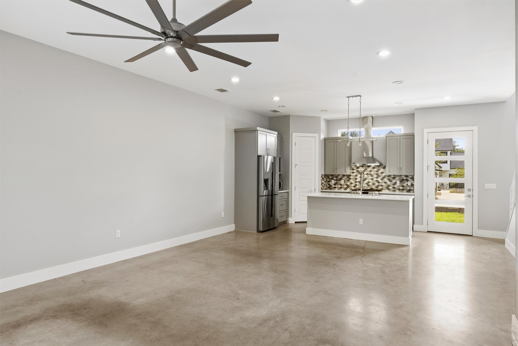 1210 Stobaugh Street, Unit B Austin, TX 78757 - Photo 40 of 40 A well-lit open floorplan connects the living area to a modern kitchen with high ceilings and a ceiling fan.