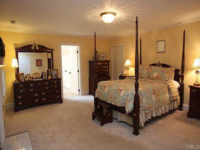 3201 Brantford Place Raleigh, NC 27607 - Photo 7 of 12 a spacious bedroom with a bed a dresser and a chandelier
