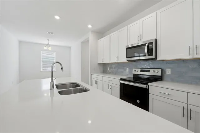 a kitchen with granite countertop a sink stainless steel appliances and white cabinets