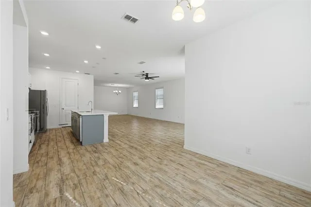 a view of a kitchen with kitchen island a sink wooden floor and a refrigerator