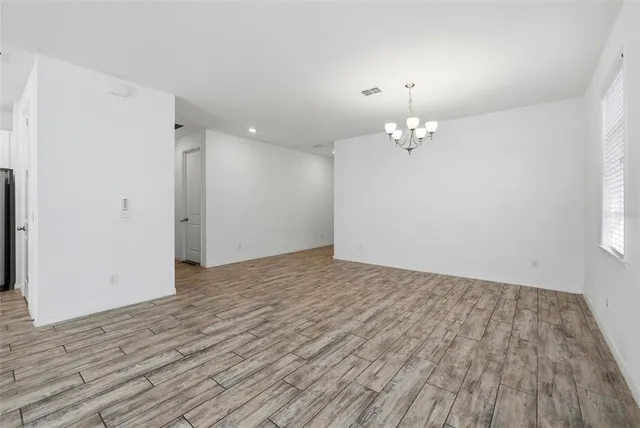 wooden floor in an empty room with a chandelier