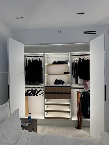a view of walk in closet with clothes and shoes