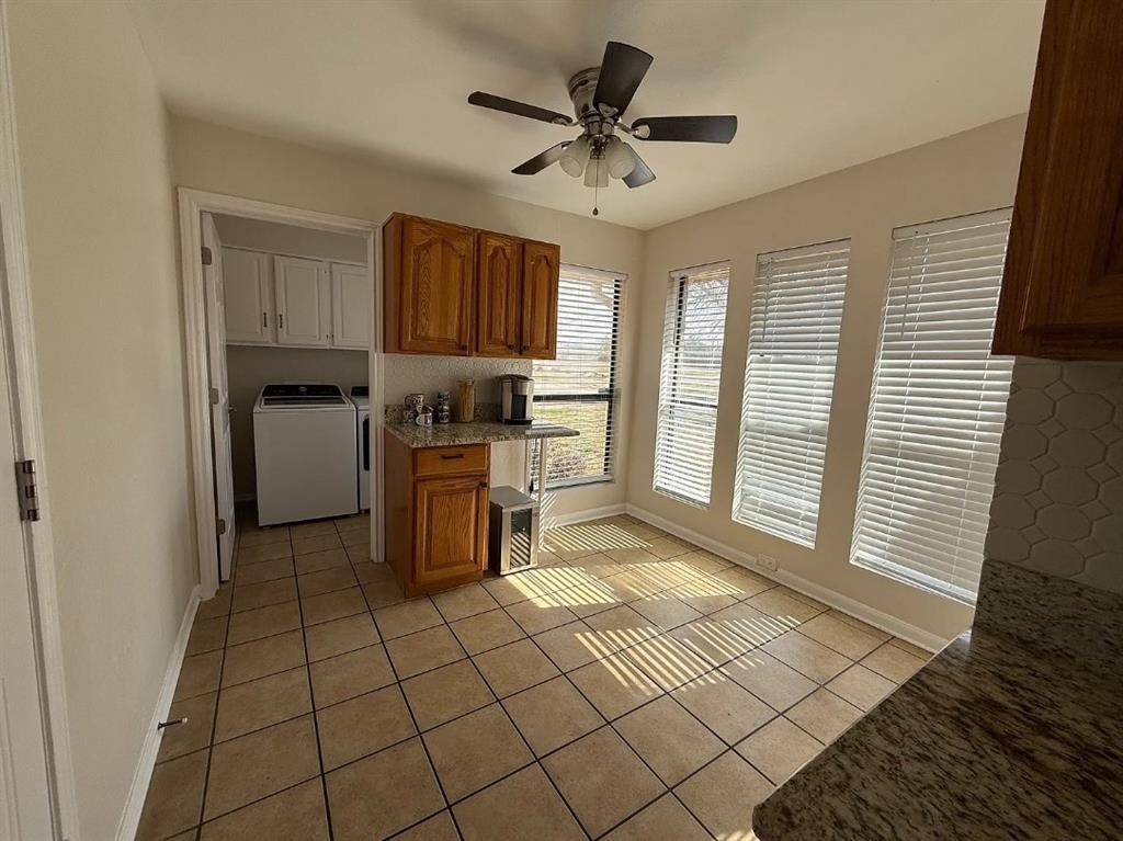 6505 Mc Cormick Ranch Court Plano, TX 75023 - Photo 10 of 21 Kitchen area featuring tile flooring, three large windows with blinds, wood cabinetry, and a ceiling fan