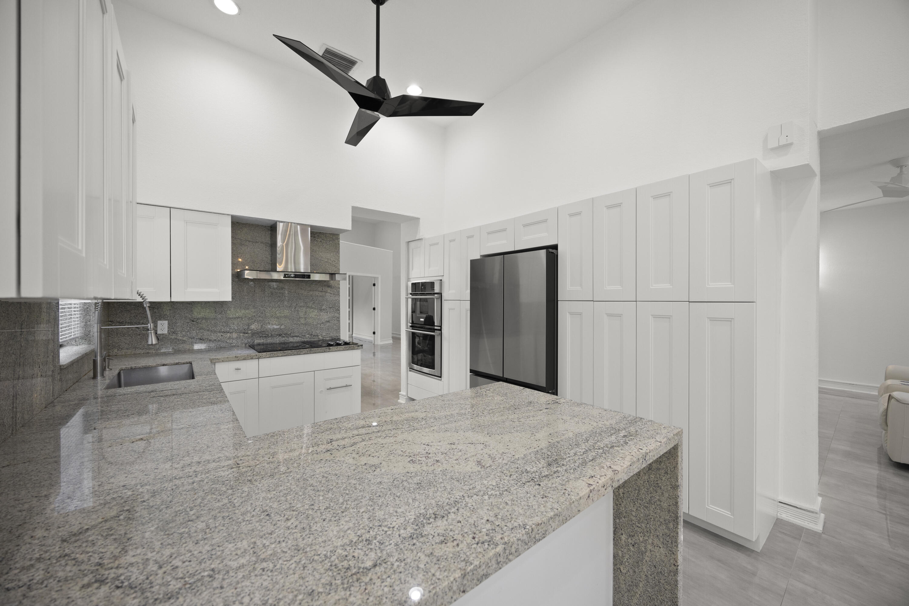 10106 Spyglass Way Boca Raton, FL 33498 - Photo 36 of 56 a kitchen with stainless steel appliances granite countertop a sink a stove a refrigerator a washer dryer and white cabinets