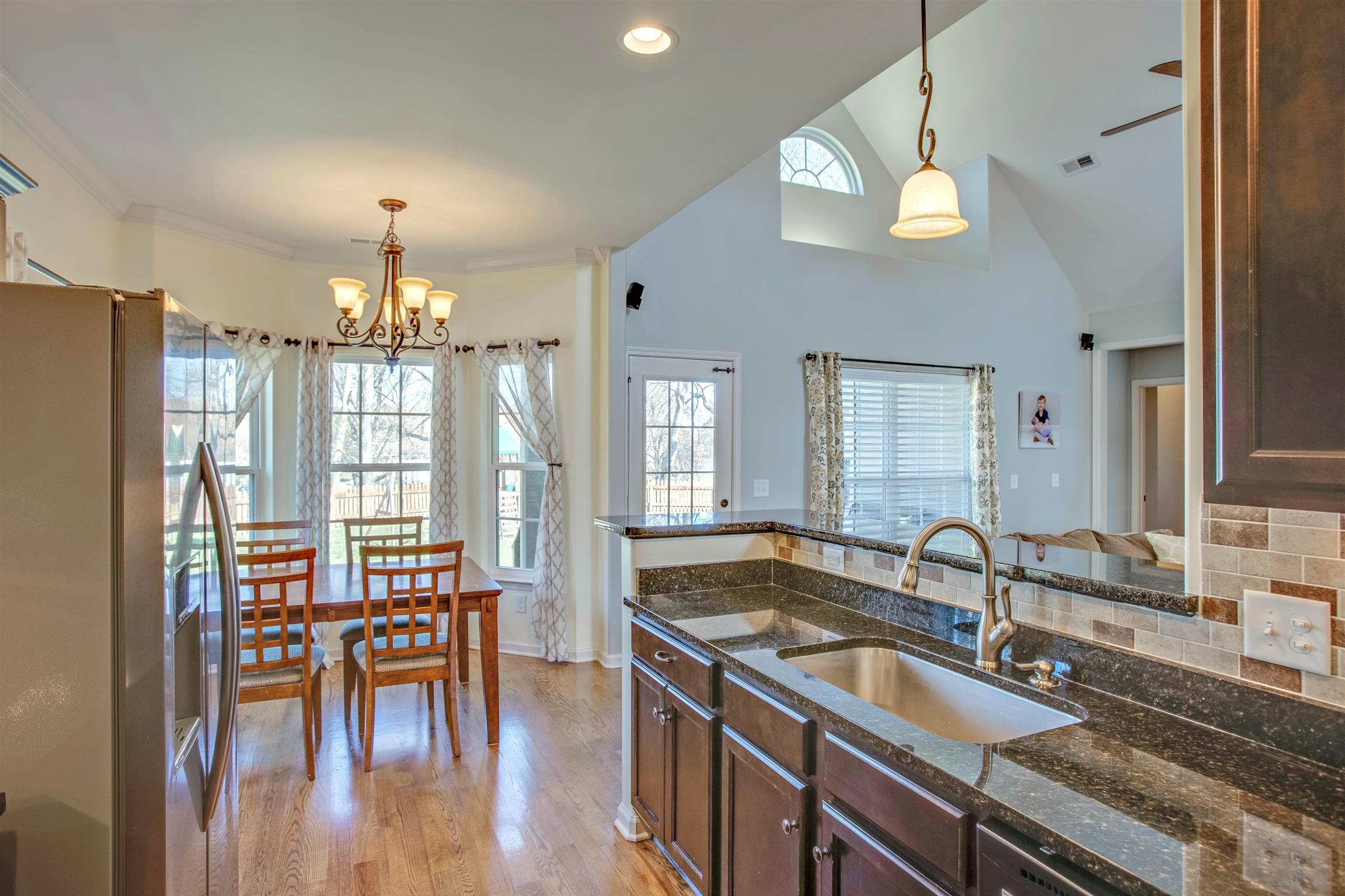 1080 Golf View Way Spring Hill, TN 37174 - Photo 13 of 28 a kitchen with granite countertop a stove a sink a dining table and chairs