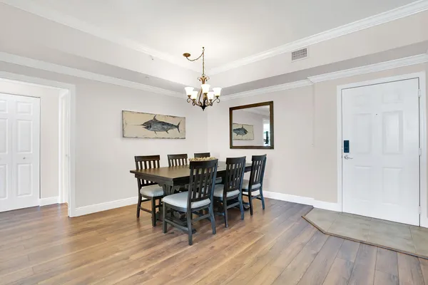 a dining room with wooden floor a chandelier a wooden table and chairs