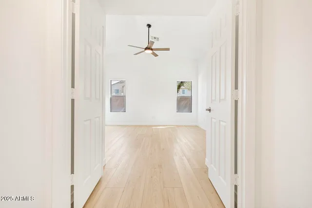 an empty room with wooden floor ceiling fan and windows