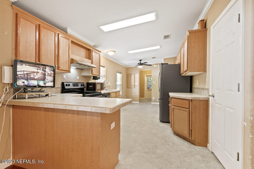 18066 Wells Road Jacksonville, FL 32234 - Photo 12 of 50 a kitchen with a refrigerator a stove a sink dishwasher and wooden cabinets