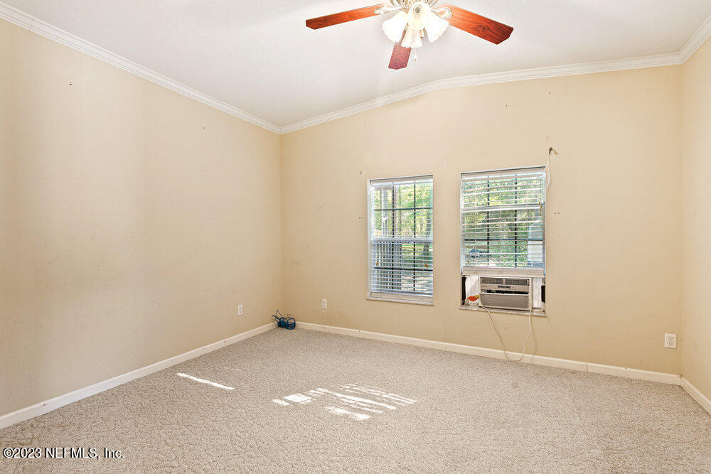 18066 Wells Road Jacksonville, FL 32234 - Photo 29 of 50 an empty room with chandelier fan and windows